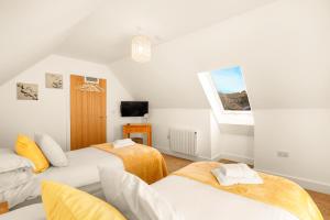 a bedroom with two beds and a tv at Yeavering - North East Escapes in Wooler