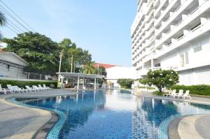 a swimming pool with chairs and a building at Welcome Plaza Hotel Pattaya in Pattaya Central
