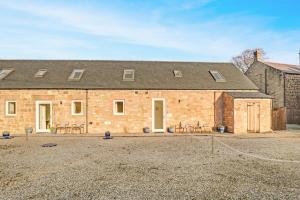 a large brick building with tables and chairs in front of it at Yeavering - North East Escapes in Wooler
