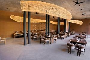 a restaurant with tables and chairs and a large chandelier at Ayana Villa By KPM in Varagampadi