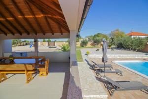 een terras met een tafel en stoelen en een zwembad bij Villa Zrilic ZadarVillas in Perušić Benkovački