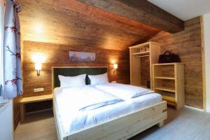 een slaapkamer met een groot bed met een houten wand bij Appartements Alpenland in Lermoos