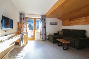 een woonkamer met een groene bank en een tv bij Appartements Alpenland in Lermoos