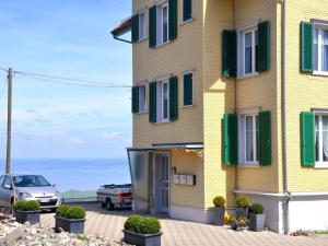 a yellow building with green shutters and a car parked next to it at Apartment Rätia by Interhome in Wolfhalden 
