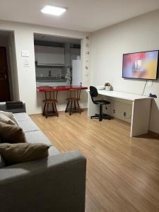 a living room with a couch and a table and a kitchen at Aconchego in Maringá