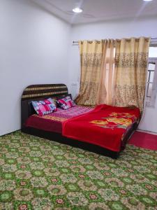 a bedroom with a bed with red sheets and curtains at Gulmarg View Guest House in Khor