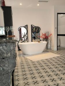 ein Badezimmer mit einer weißen Badewanne und einem Spiegel in der Unterkunft Villa Meyer Demeure Remarquable chambre d'hôtes standing indépendante in Béziers