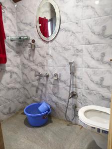 a bathroom with a toilet and a mirror and a bucket at Gulmarg View Guest House in Khor