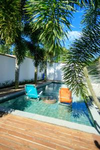two chairs sitting next to a swimming pool with palm trees at Casa George Trancoso in Trancoso