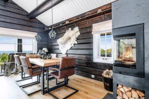 ein Esszimmer mit einem Kamin sowie einem Tisch und Stühlen in der Unterkunft Family-Friendly Log Cabin With Panoramic View in Østby