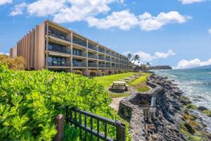 a building on a cliff next to the ocean at Kaleialoha 210 · KA 210 OceanFront 1BD Tropical Getaway w AC in Kahana