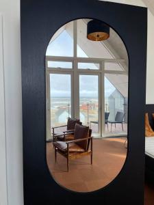 a mirror in a room with a chair and a window at Hotel og Restaurant Havbadet in Thisted