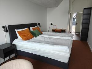 a bed with orange and green pillows in a room at Hotel og Restaurant Havbadet in Thisted