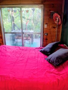 a red bed with pillows in a room with a window at Casita isleña in Tigre