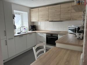 una cucina con mobili bianchi e un tavolo di legno di Ferienwohnung Marienhof Erdgeschoss a Seelbach