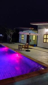 a pool with purple lights in front of a house at Nan poolvilla in Ban Kot +4 photos