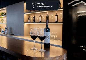 two wine glasses sitting on a counter with a bottle of wine at Hotel Palermitano by DOT Boutique in Buenos Aires