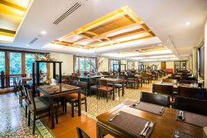 un restaurant avec des tables et des chaises en bois ainsi que des fenêtres dans l'établissement Dor-Shada Resort By The Sea, à Na Jomtien