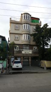 een gebouw waar een auto voor geparkeerd staat bij Pandora Motel in Yangon