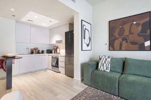 a living room with a green couch and a kitchen at The Poet Den with 120 inch screen in Yas Island