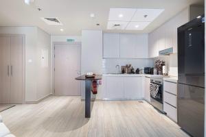 a kitchen with white cabinets and a table in it at The Poet Den with 120 inch screen in Yas Island