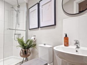 een badkamer met een wastafel, een toilet en een spiegel bij Thimble Cottage in St Bees