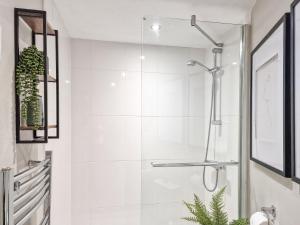 een witte badkamer met een douche en een plant bij Thimble Cottage in St Bees +7 foto's