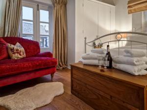 een woonkamer met een rode bank en een tafel met handdoeken bij Thimble Cottage in St Bees
