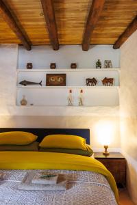 a bedroom with a yellow bed and some shelves at Casa Com Mãos in Marvão