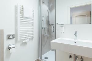 ein weißes Badezimmer mit Waschbecken und Dusche in der Unterkunft Heideblick - Tagungs- und Freizeithotel an der Lüneburger Heide in Jesteburg