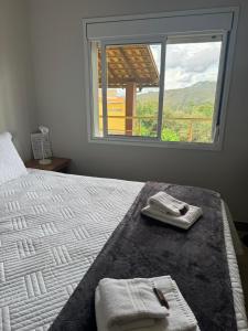 a bedroom with a bed with towels and a window at Vila dos Cristais - Apartamentos de Temporada in Alto Paraíso de Goiás