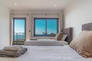 een slaapkamer met twee bedden en een groot raam bij Camara De Lobos Lux Villa in Câmara de Lobos +44 foto's