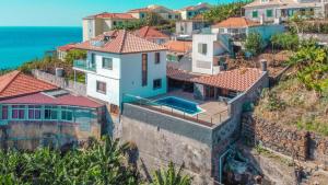 een huis op een heuvel naast de oceaan bij Camara De Lobos Lux Villa in Câmara de Lobos