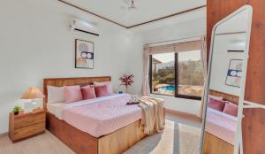 a bedroom with a bed with pink pillows and a window at SaffronStays Green Lawns in Pāli +41 photos
