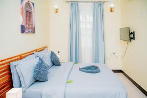 a bedroom with a bed with blue pillows and a window at Roots and Waves in Zanzibar City