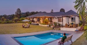 a house with a swimming pool in front of a house at SaffronStays Green Lawns in Pāli