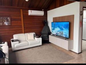 ein Wohnzimmer mit einem weißen Stuhl und einem TV in der Unterkunft Angra dos Reis - Píer 600 casa 4 in Angra dos Reis