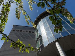 a tall building with glass windows and a tree at Sofitel Luxembourg Europe in Luxembourg