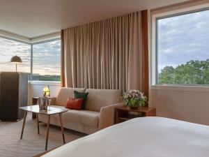 a hotel room with a bed and a couch and a window at Sofitel Luxembourg Le Grand Ducal in Luxembourg