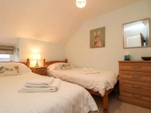 a bedroom with two beds and a dresser and a mirror at Beacon Cottage in Pickering