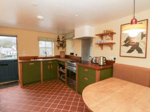 a kitchen with green cabinets and a wooden table at Fronglyd in Cardigan +20 photos