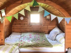 Bett in einem Blockhaus mit Fenster in der Unterkunft Rivendell Glamping Pod - Uk11881 in North Tamerton