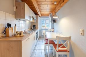 een keuken met witte kasten en een tafel en stoelen bij Schipp Landen Johanna in Schobüll