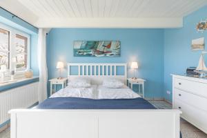 una camera da letto con pareti blu e un letto con due tavoli di Schipp Landen Lisa a Schobüll