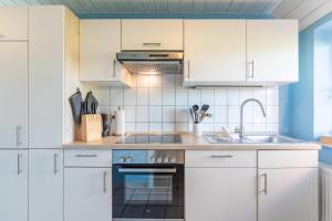 una cucina con mobili bianchi e un lavandino di Schipp Landen Lisa a Schobüll