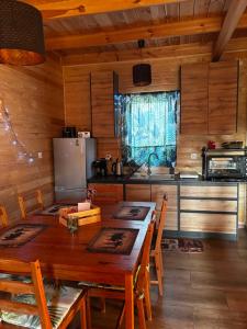 een keuken met een houten tafel en een koelkast bij Gawra Nad Jeziorem - całoroczne domki nad jeziorem z balią, jacuzzi i sauną, Kaszuby in Sobącz