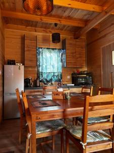 een keuken met een houten tafel met stoelen en een koelkast bij Gawra Nad Jeziorem - całoroczne domki nad jeziorem z balią, jacuzzi i sauną, Kaszuby in Sobącz +51 foto's