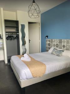 ein Schlafzimmer mit einem großen Bett mit einer blauen Wand in der Unterkunft Logis Hotel- Restaurant La Haie Des Vignes Séminaires et Evènementiel in Allain