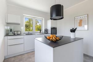 a white kitchen with a bowl of fruit on a counter at De Bööi - Luxus-Haus mit Meerblick, Sauna & Kamin in Fehmarn