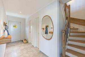a hallway with a round mirror and a staircase at De Bööi - Luxus-Haus mit Meerblick, Sauna & Kamin in Fehmarn